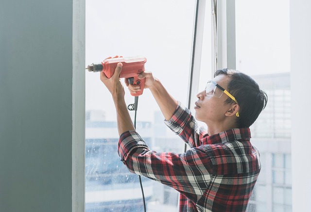 Person in safety glasses drilling into a window frame during home maintenance